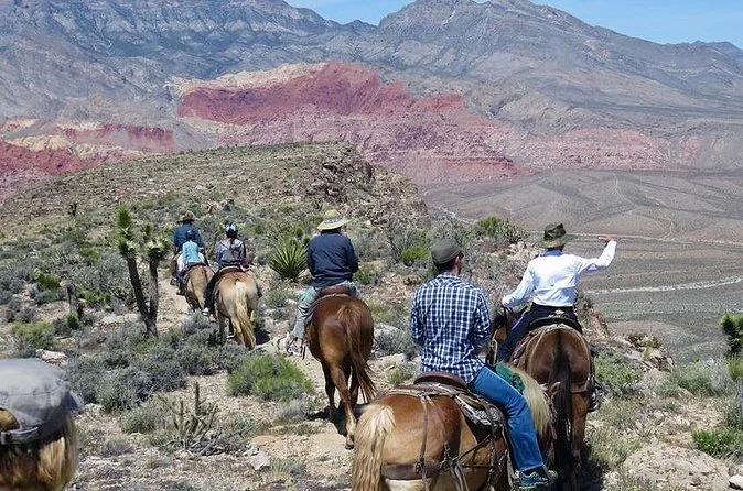 Reiter von hinten auf einem Trail, vor ihnen die bunten Hügel von Red Rock